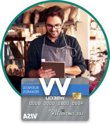 围裙里的店主拿着牌匾. 下面是WSECU白金商务奖励Visa卡的图片. 